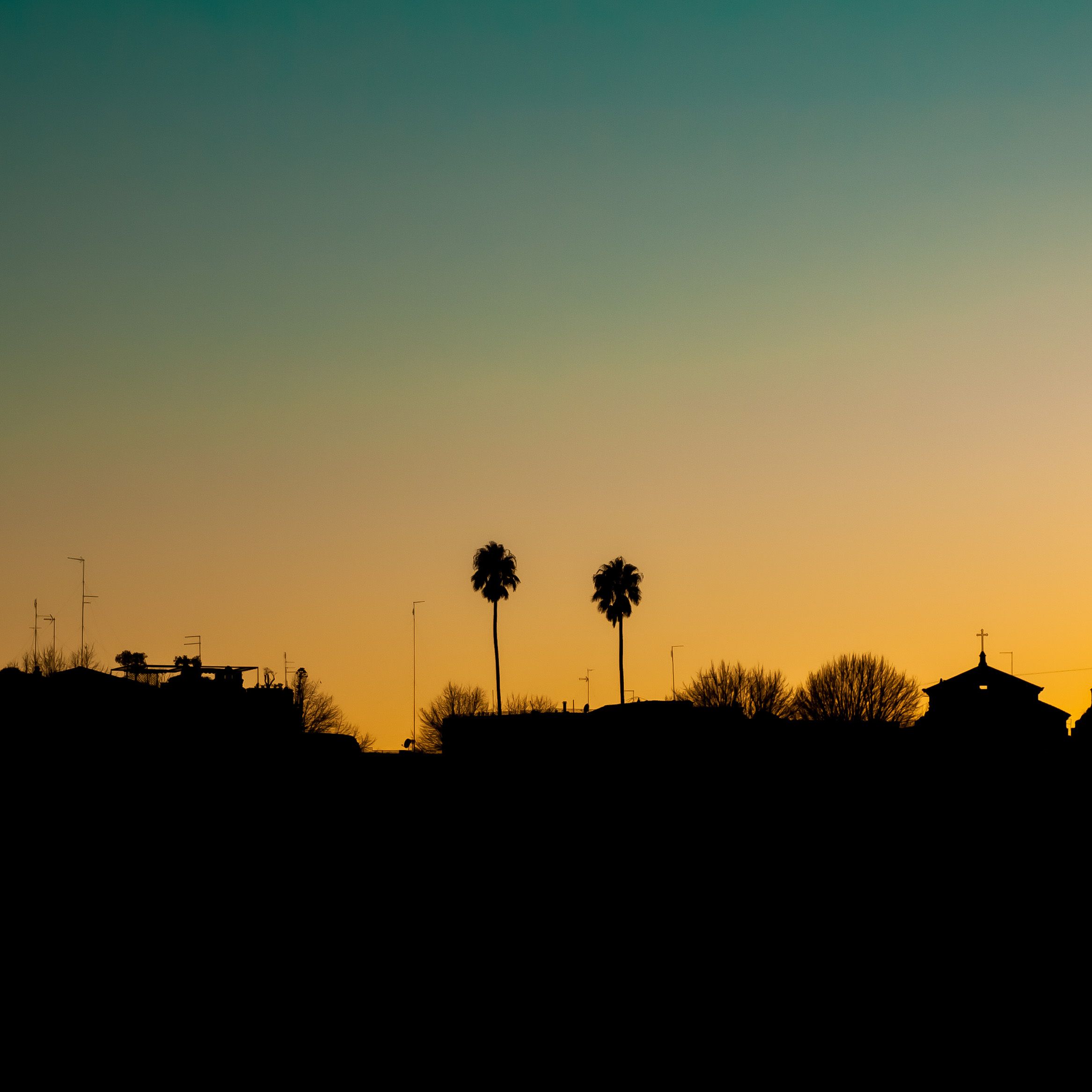 Silhouette of trees and buildings against a vibrant sunset sky, creating a peaceful and serene atmosphere.