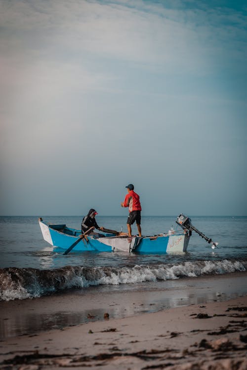 People Riding on a Wooden Boat Near the Seashore