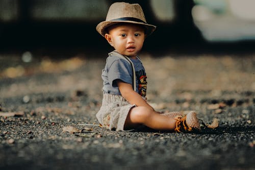 Free Child In Grey Shorts Sitting On Road Stock Photo