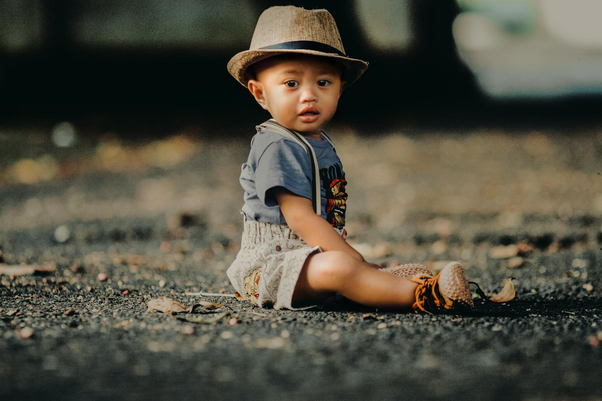 Child In Grey Shorts Sitting On Road