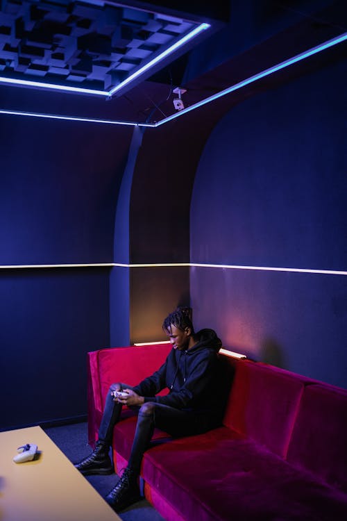 Man in Black Jacket Sitting on Red Couch