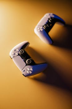 Two modern video game controllers on a gradient surface with dramatic lighting.