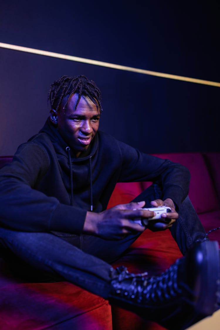 Man Sitting On Couch With Feet On Table Holding A Game Pad