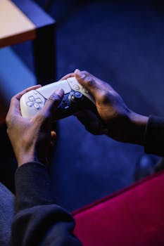 Close-up of hands holding a video game controller in a dimly lit room, perfect for gaming themes.