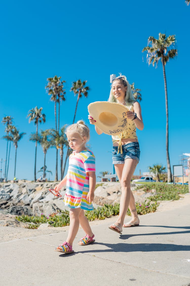 A Woman Following Her Child While Holding A Hat