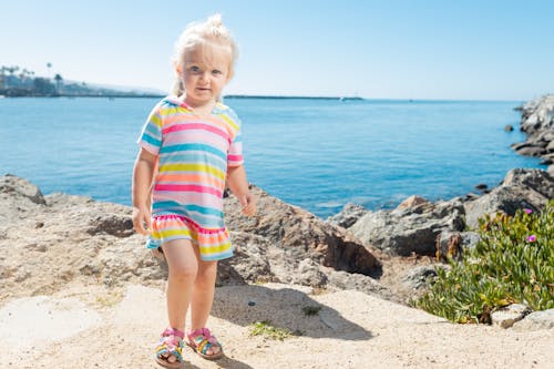 A Cute Girl in Colorful Dress Standing Near the Beach