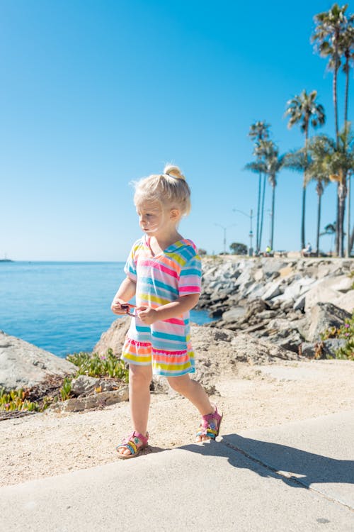 A Young Girl in Colorful Dress Standing Near the Ocean