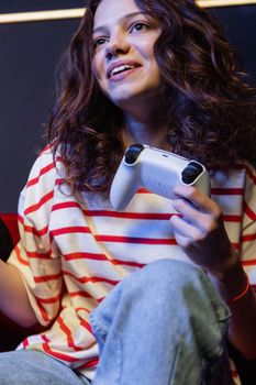 Smiling woman playing video games indoors, holding controller and having fun.