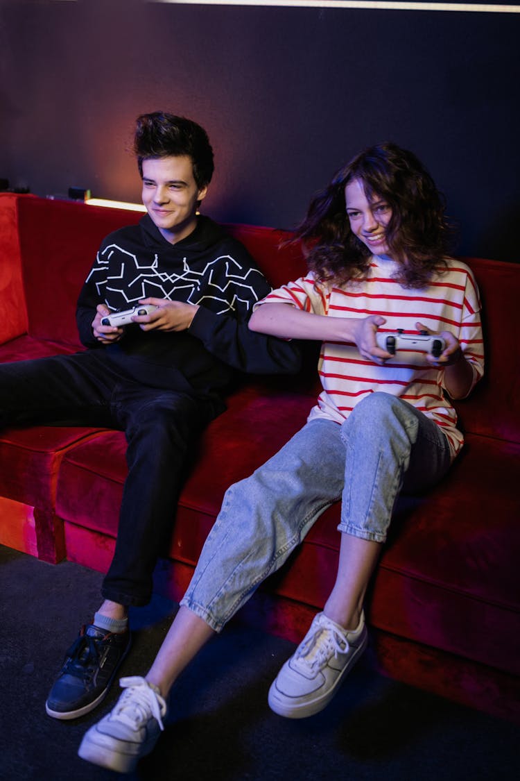 A Man And A Woman Playing Video Games While Sitting On A Sofa