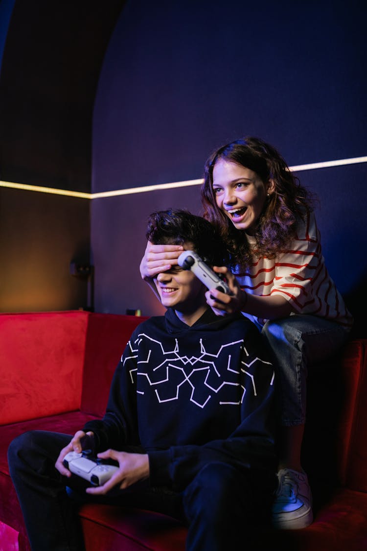 A Man And A Woman Playing Video Games While Sitting On A Sofa