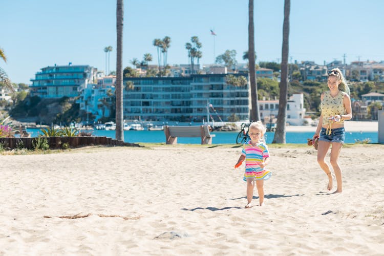 Mother And Daughter Walking On Beach Sand