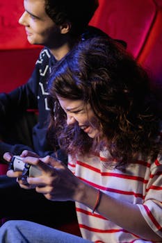 Two teenagers having fun playing a video game indoors, showcasing happy emotions.