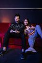 Man and Woman Sitting on Red Couch