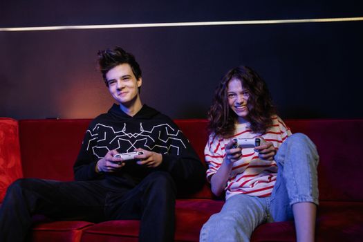 Two teenagers playing video games together, smiling and having fun indoors.