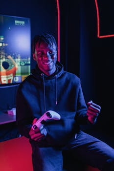African American man holds a game controller, smiling in a neon-lit room, enjoying video gaming.