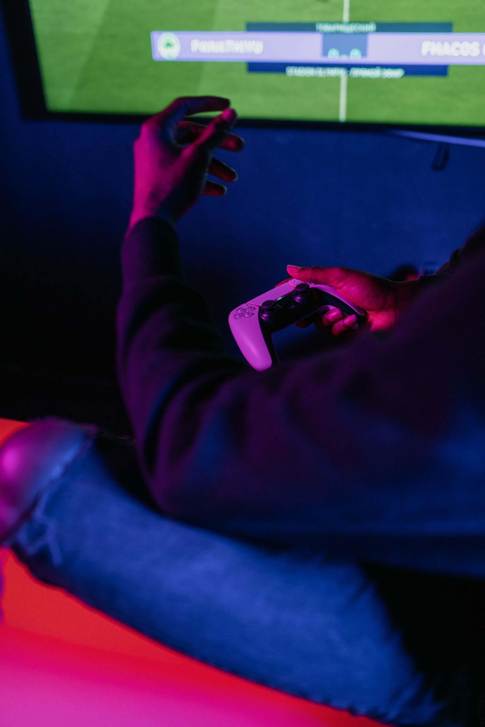 Hands holding a game controller in neon lighting