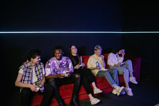 A diverse group of friends enjoying video games, laughing and having fun indoors.