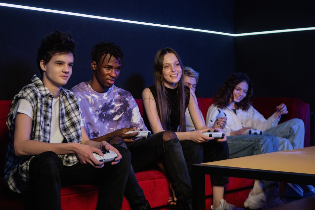 Gruppo di amici sul divano che giocano a videogiochi insieme nella stessa stanza