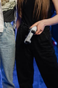 Woman holding a video game controller wearing casual clothing, focus on controller.