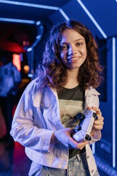 Smiling teenage girl holds a game controller in a vibrant gaming arcade setting.