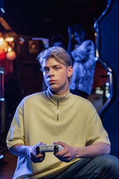 A young man intently plays video games in a neon-lit room, holding a controller.