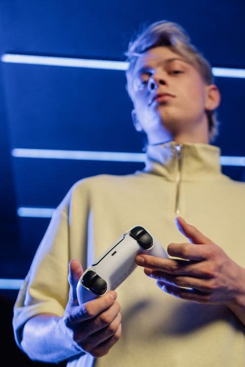 Free Teen focusing on gaming in a modern setting, holding a console controller. Stock Photo
