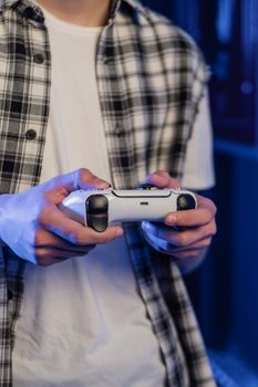 Close-up of a teenager holding a gaming controller indoors, engaged in gaming.