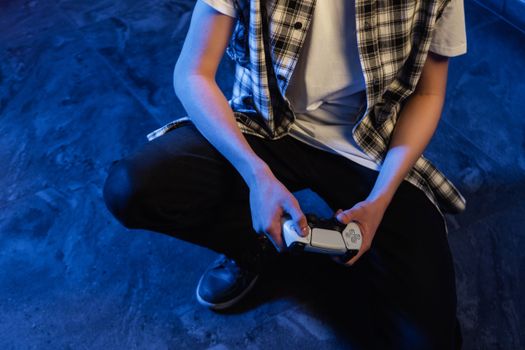 A young person intensely focused on gaming with a joystick in a blue-lit room.