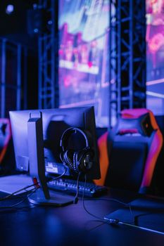 A modern gaming setup featuring a computer monitor and headset in a neon-lit environment.