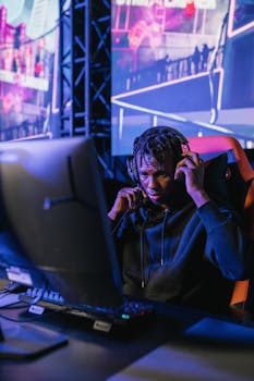 Focused young man wearing headphones deeply engaged in an intense gaming session indoors.