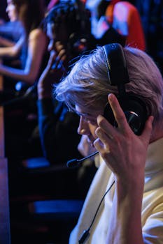 A young adult immersed in a gaming tournament, wearing a headset and focusing intently on the screen.