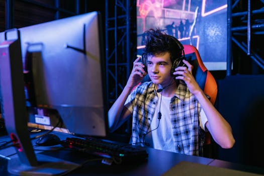 Teenage boy gaming at a computer station with headset during e-sports event.