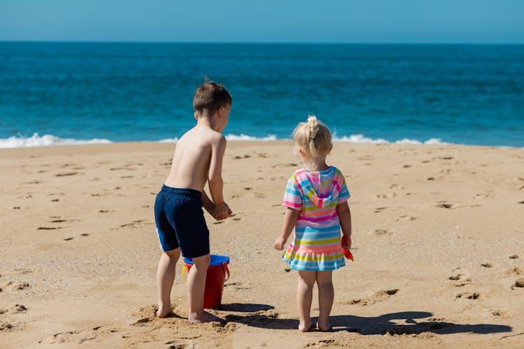 Kids Standing On Beach Sand