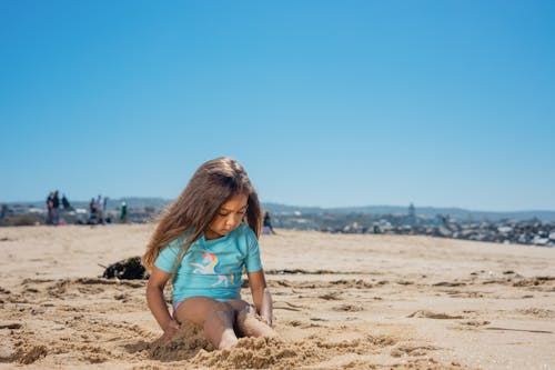 Little Girl Sitting on Beach Sand