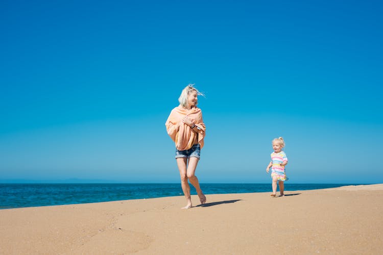 A Mother And Daughter Running At The Beach