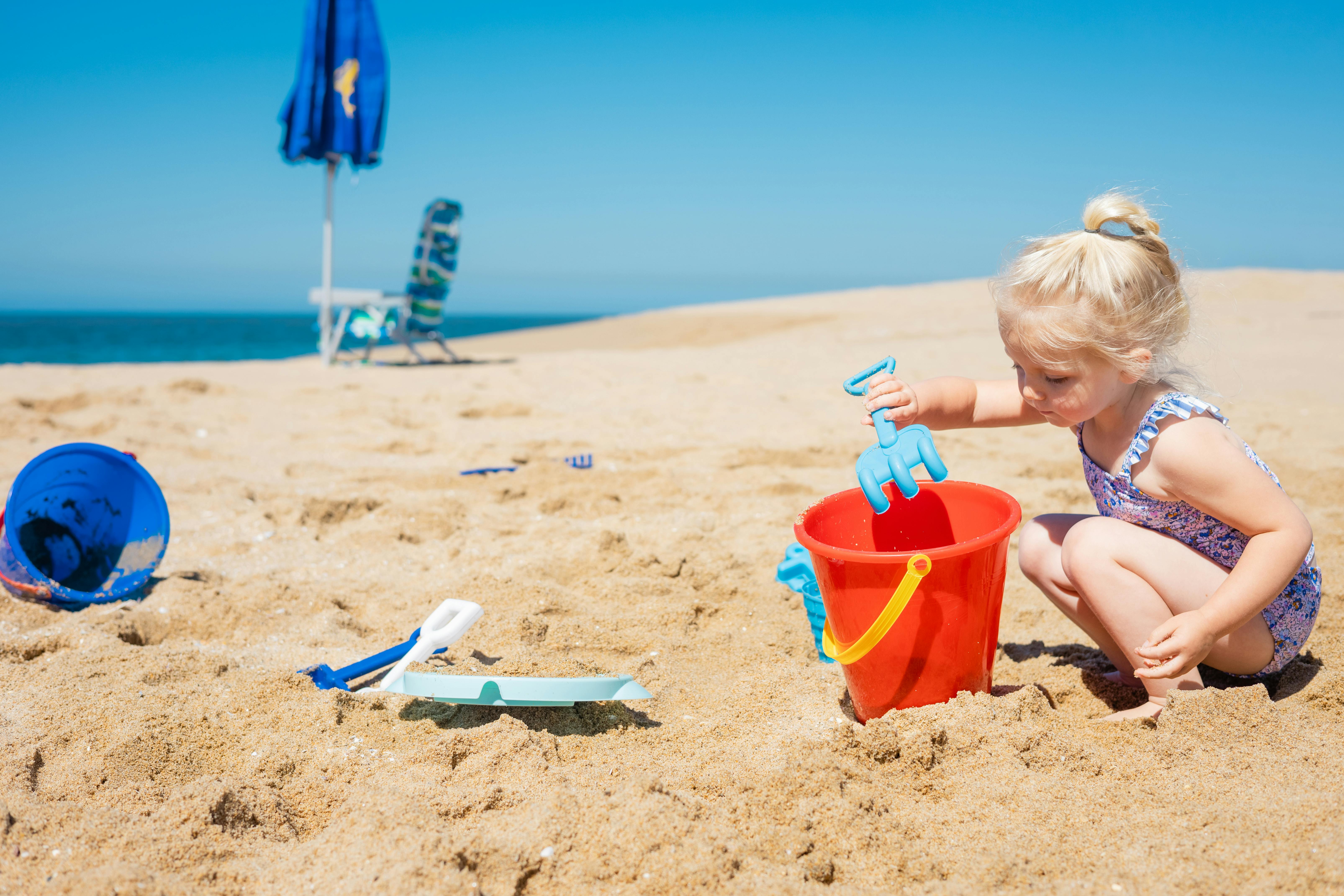 photo of a girl playing with her toys at the beach