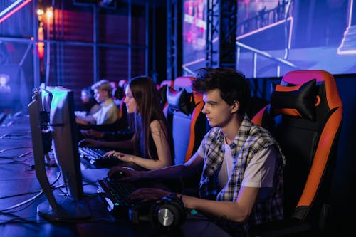 People Sitting on Black and Orange Chair Playing Computer Games