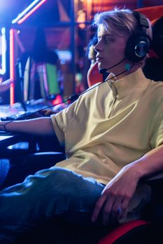 Focused gamer with headphones, immersed in high-tech gaming environment.