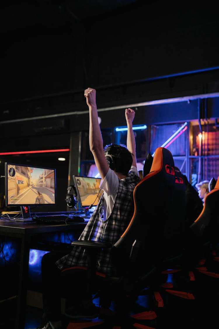 A Boy Raising His Hands While Gaming