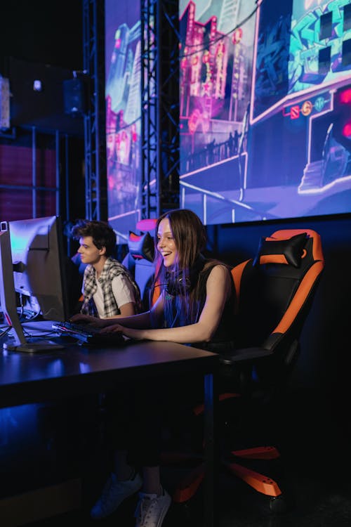 Free A Man and Woman Sitting on a Gaming Chair while Playing Video Games Stock Photo