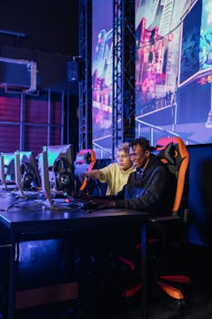 Two teenagers playing video games on gaming chairs with large monitors in a modern setup.