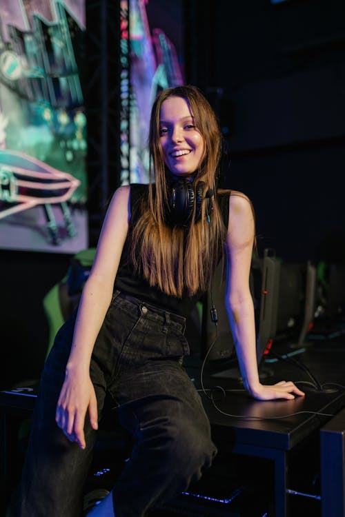 Woman in Black Tank Top and Black Denim Jeans Sitting on Black Computer Table