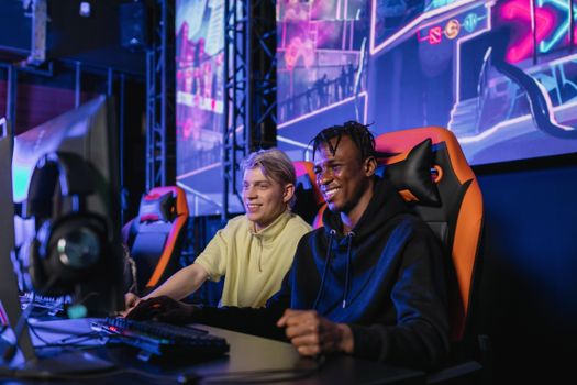 Two young men enjoying a competitive gaming session at an eSports event. Indoors with neon lights.