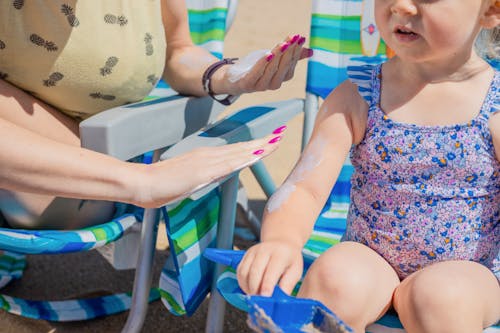 Free A Person Applying Sunscreen on a Young Girl's Arm Stock Photo