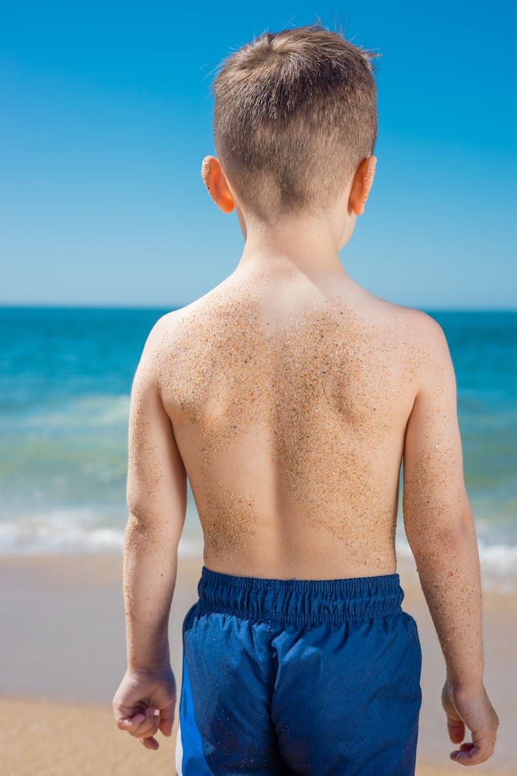 A Back View Of A Young Boy With Sand On Skin