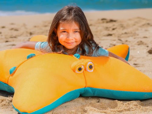 A Young Girl Lying on the Plush Toy on the Sand