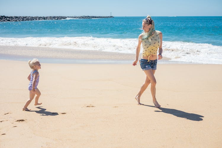 A Daughter And Her Mother Running Near The Sea