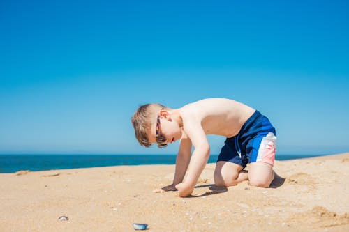 A Boy with Sunglasses Playing with Sand