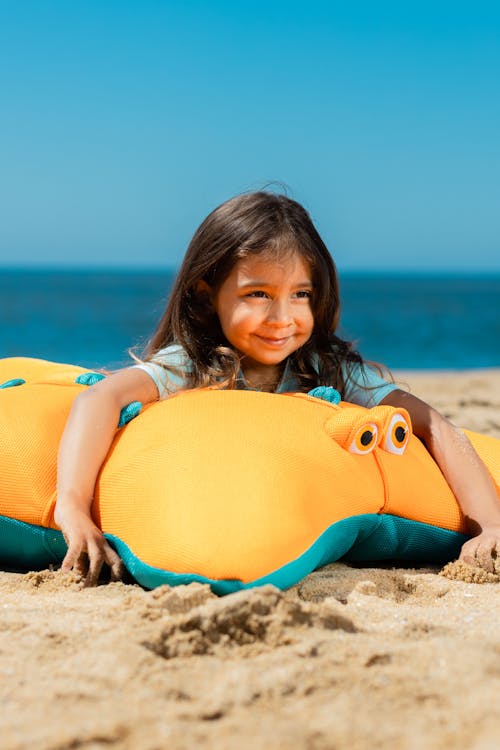 Free A Young Girl Lying on the Plush Toy at the Beach Sand Stock Photo