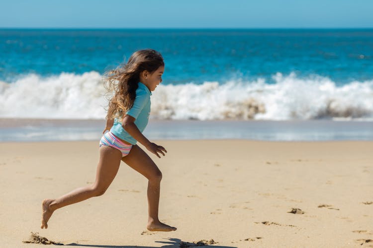 A Young Girl Running On The Beach